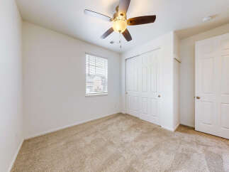 Step into this inviting bedroom featuring a plush carpeted floor and a convenient ceiling fan for year-round comfort.