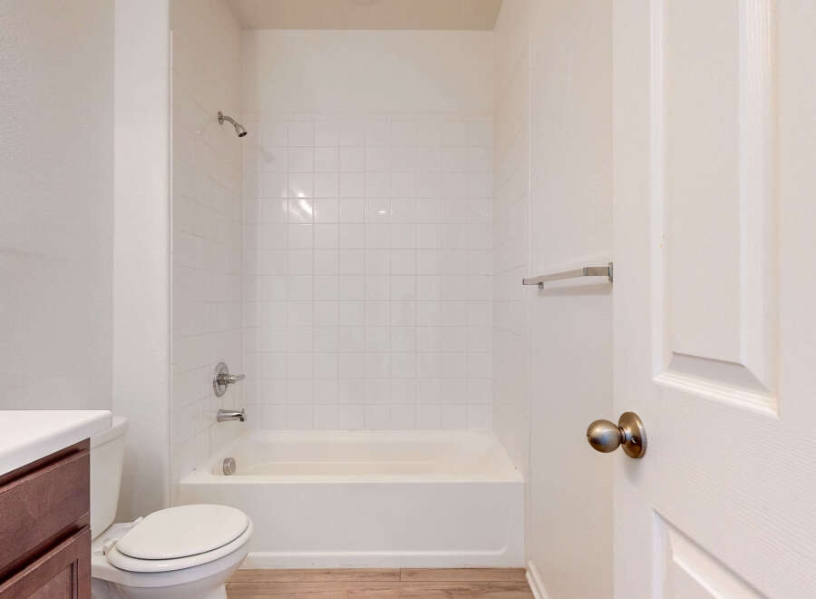This bathroom features a pristine white tiled shower and tub combination, perfect for relaxing soaks.