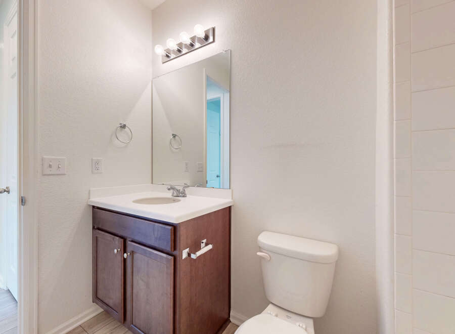 This bathroom features a modern vanity with ample storage and a sleek countertop, complemented by a large mirror and bright vanity lighting.