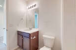 This bathroom features a modern vanity with ample storage and a sleek countertop, complemented by a large mirror and bright vanity lighting.