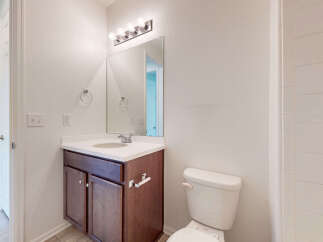 This bathroom features a modern vanity with ample storage and a sleek countertop, complemented by a large mirror and bright vanity lighting.