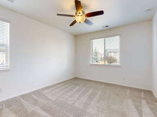This spacious bedroom features plush carpeting and a ceiling fan for comfort.