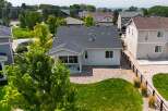 Discover this charming home featuring a spacious backyard with lush green grass and a gravel patio, perfect for outdoor entertaining.
