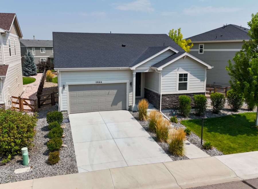 Discover this charming single-family home featuring a modern gray garage door and a welcoming entryway with stone accents.