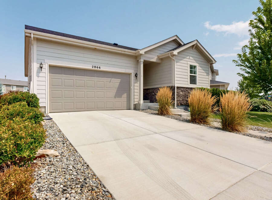 This charming single-family home features a spacious concrete driveway leading to a two-car garage, perfect for vehicle storage and workspace.