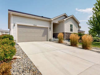 This charming single-family home features a spacious concrete driveway leading to a two-car garage, perfect for vehicle storage and workspace.