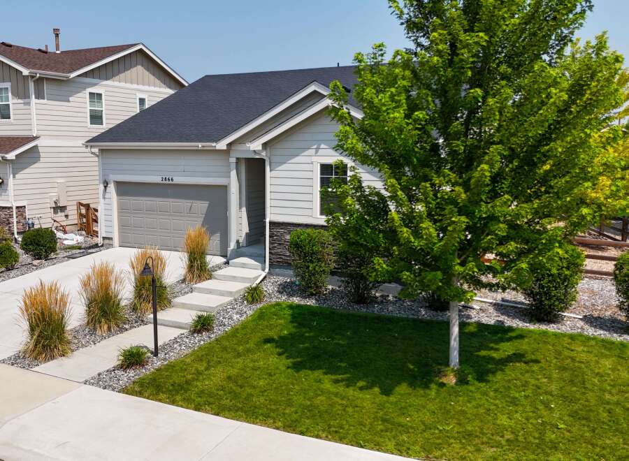 Discover this charming single-family home featuring a modern exterior with light gray siding and stone accents.