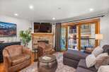 Experience modern mountain living in this beautifully appointed living room, featuring a cozy stone fireplace and a large flat-screen TV.