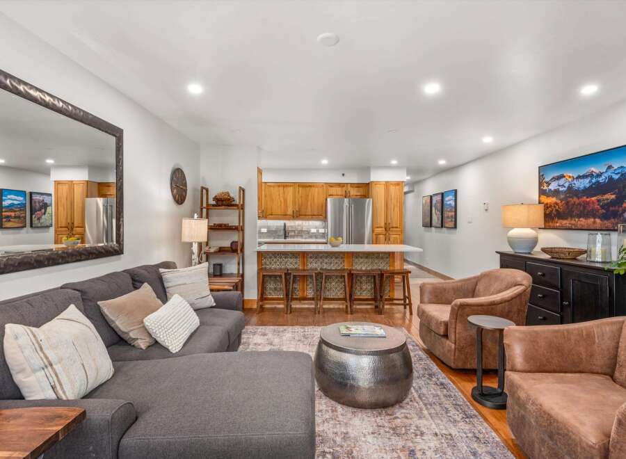 Experience modern living in this spacious open-concept living area, featuring a comfortable sectional sofa and stylish accent chairs perfect for relaxation.