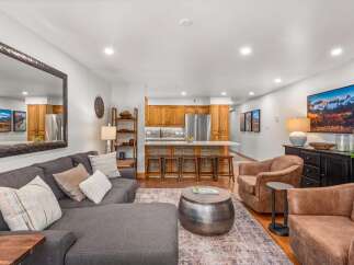 Experience modern living in this spacious open-concept living area, featuring a comfortable sectional sofa and stylish accent chairs perfect for relaxation.