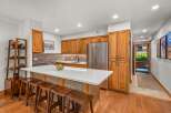 This stunning kitchen features warm, natural wood cabinetry that complements the sleek white countertops and modern stainless steel appliances.
