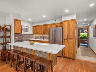 This stunning kitchen features warm, natural wood cabinetry that complements the sleek white countertops and modern stainless steel appliances.