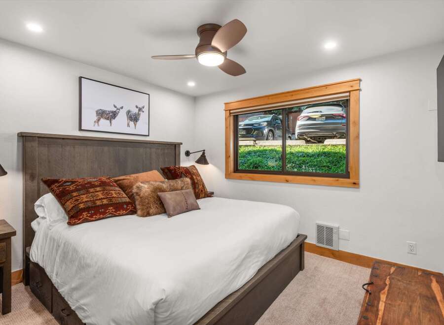 Experience rustic charm in this cozy bedroom, featuring a king-size bed adorned with plush, patterned pillows and a luxurious faux fur accent.