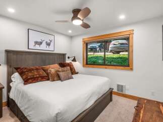 Experience rustic charm in this cozy bedroom, featuring a king-size bed adorned with plush, patterned pillows and a luxurious faux fur accent.
