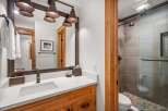 This modern bathroom features a sleek vanity with a white quartz countertop and a vessel sink, complemented by warm wood cabinetry.