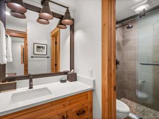 This modern bathroom features a sleek vanity with a white quartz countertop and a vessel sink, complemented by warm wood cabinetry.