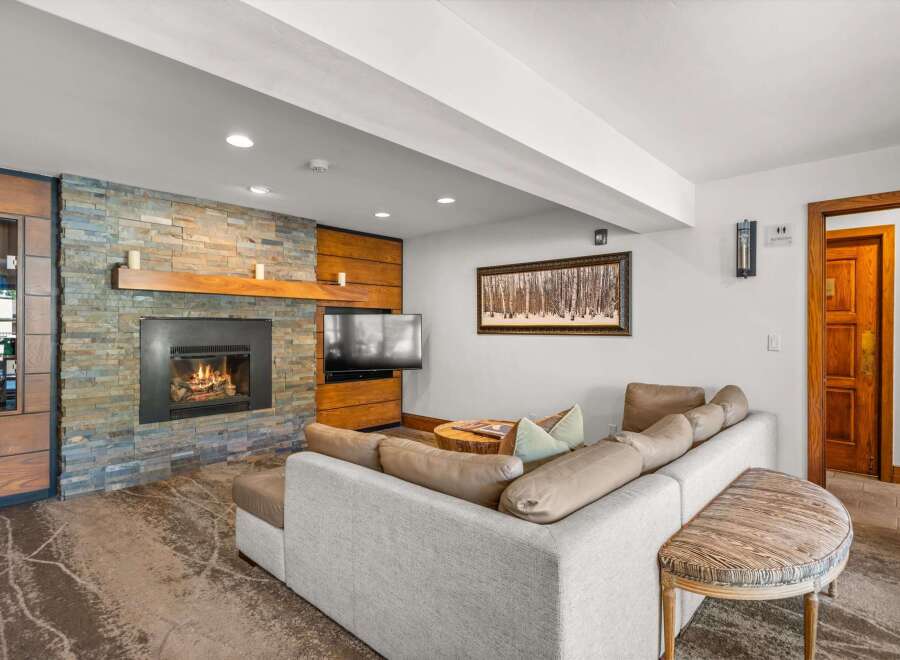Cozy up by the stone fireplace in this inviting living room, featuring a comfortable sectional sofa perfect for relaxation.
