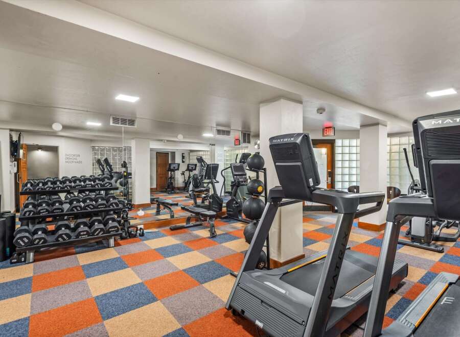 Elevate your fitness routine in this well-equipped gym, featuring a variety of cardio machines like treadmills and ellipticals, alongside a comprehensive set of free weights and benches.