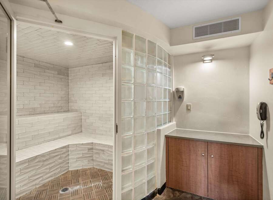 Experience ultimate relaxation in this luxurious steam room, featuring elegant white tiled walls and built-in seating for a spa-like experience.