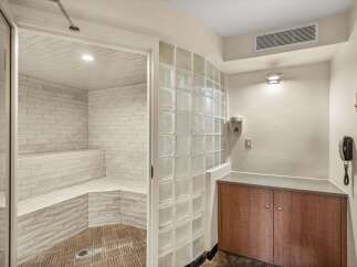 Experience ultimate relaxation in this luxurious steam room, featuring elegant white tiled walls and built-in seating for a spa-like experience.