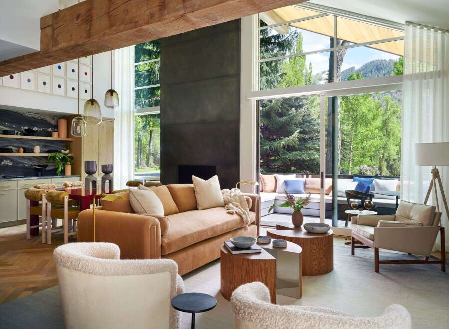 Experience modern mountain living in this stunning open-concept living space, featuring a plush burnt orange sofa and cozy boucle armchairs perfect for relaxation.