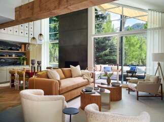 Experience modern mountain living in this stunning open-concept living space, featuring a plush burnt orange sofa and cozy boucle armchairs perfect for relaxation.