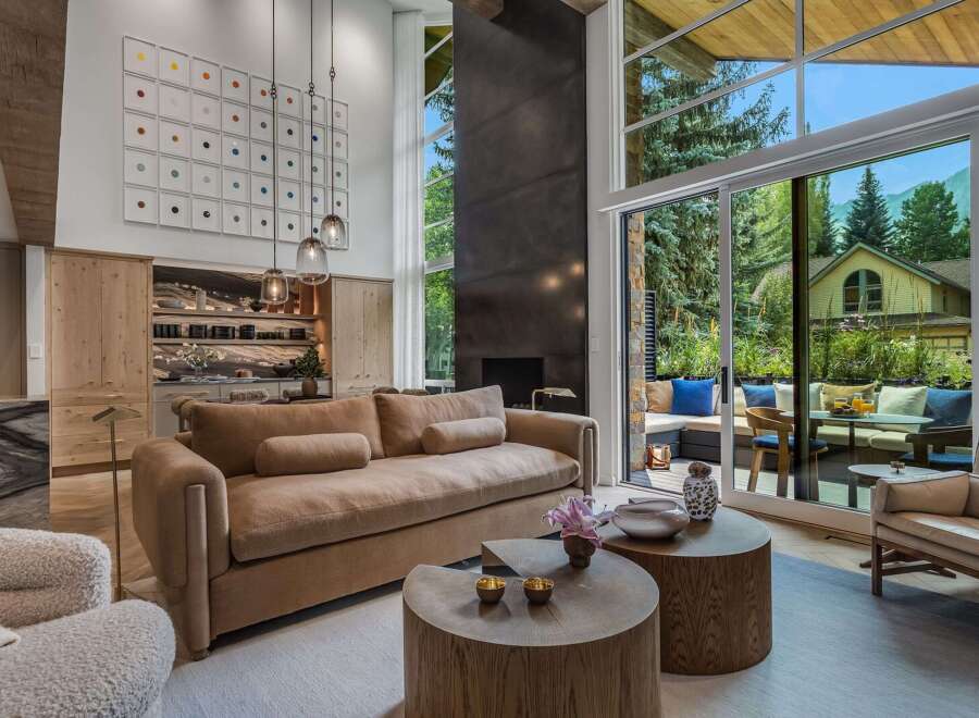 Experience luxurious living in this stunning modern home, featuring a spacious living area with a large sectional sofa and two unique wooden coffee tables.