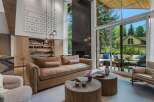 Experience luxurious living in this stunning modern home, featuring a spacious living area with a large sectional sofa and two unique wooden coffee tables.