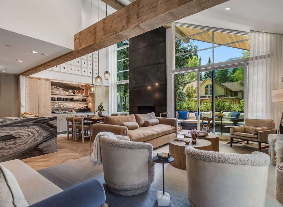 Experience luxurious living in this stunning open-concept great room, featuring a soaring ceiling with exposed wooden beams and a dramatic floor-to-ceiling fireplace.