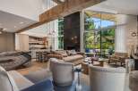 Experience luxurious living in this stunning open-concept great room, featuring a soaring ceiling with exposed wooden beams and a dramatic floor-to-ceiling fireplace.