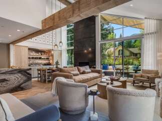 Experience luxurious living in this stunning open-concept great room, featuring a soaring ceiling with exposed wooden beams and a dramatic floor-to-ceiling fireplace.