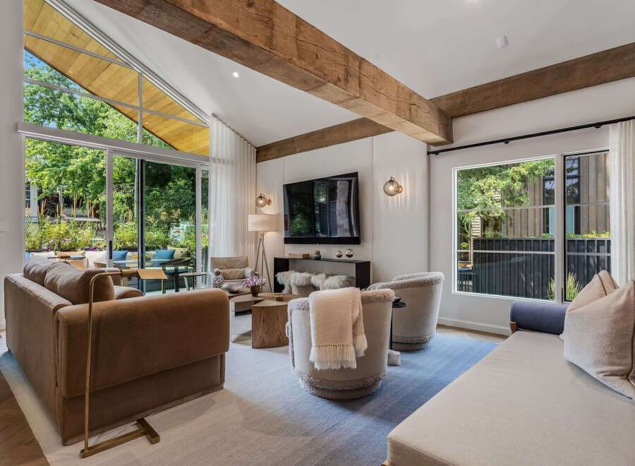 Experience modern living in this stunning living room, featuring soaring vaulted ceilings with exposed wooden beams and expansive windows that flood the space with natural light.