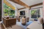 Experience modern living in this stunning living room, featuring soaring vaulted ceilings with exposed wooden beams and expansive windows that flood the space with natural light.