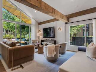 Experience modern living in this stunning living room, featuring soaring vaulted ceilings with exposed wooden beams and expansive windows that flood the space with natural light.