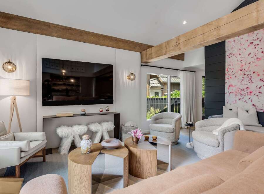 Experience modern living in this stylish living room, featuring exposed wooden beams and a large flat-screen TV.