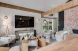 Experience modern living in this stylish living room, featuring exposed wooden beams and a large flat-screen TV.