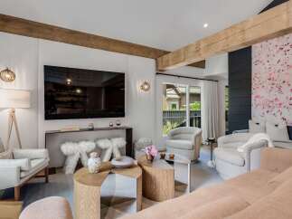 Experience modern living in this stylish living room, featuring exposed wooden beams and a large flat-screen TV.