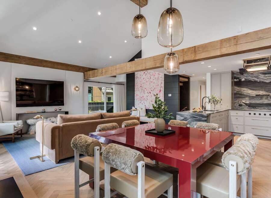Experience modern luxury in this open-concept living space, featuring a striking red dining table as the centerpiece.
