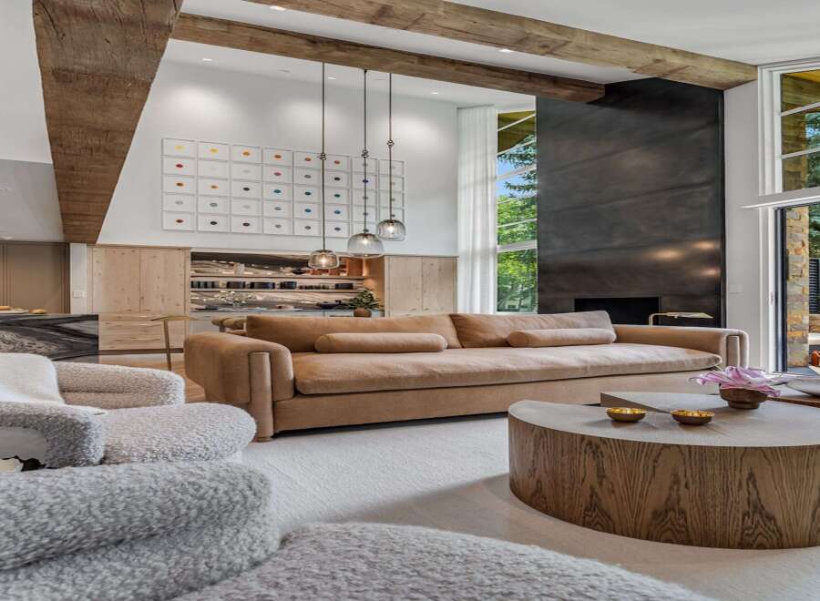 Experience luxury living in this stunning modern home, featuring a spacious living area with a large sectional sofa and a striking metal fireplace.