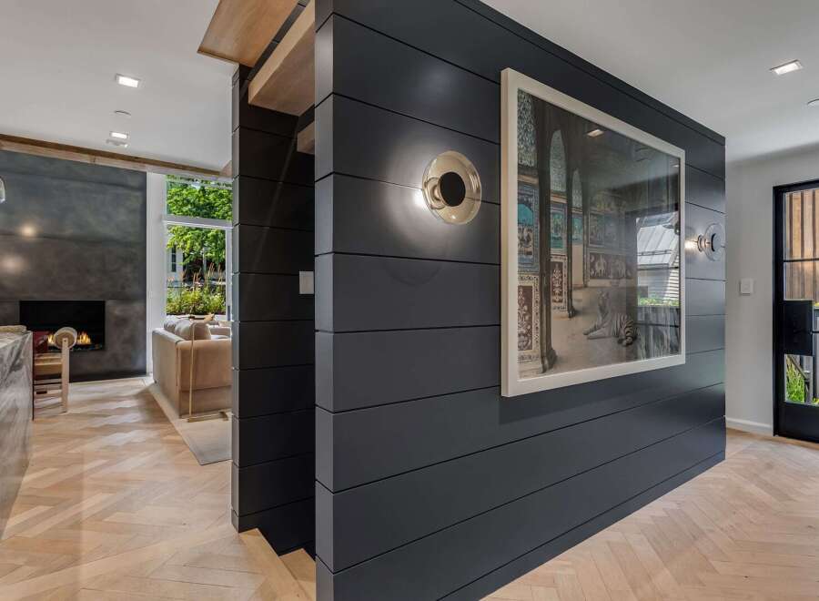 Experience modern luxury in this stunning home featuring a sleek dark wood accent wall adorned with captivating artwork and contemporary lighting.