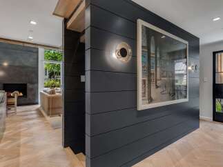 Experience modern luxury in this stunning home featuring a sleek dark wood accent wall adorned with captivating artwork and contemporary lighting.