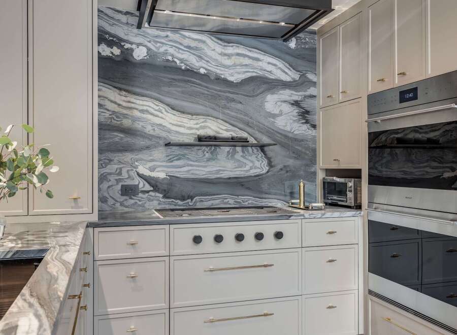 Experience luxury in this stunning kitchen featuring a dramatic marble backsplash with captivating grey and white veining.