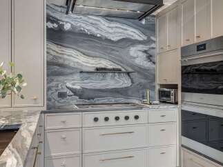 Experience luxury in this stunning kitchen featuring a dramatic marble backsplash with captivating grey and white veining.
