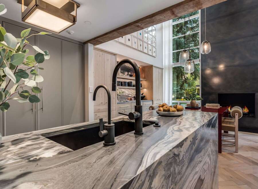 Experience luxury in this modern kitchen featuring a stunning marble island with a deep sink and sleek faucets.