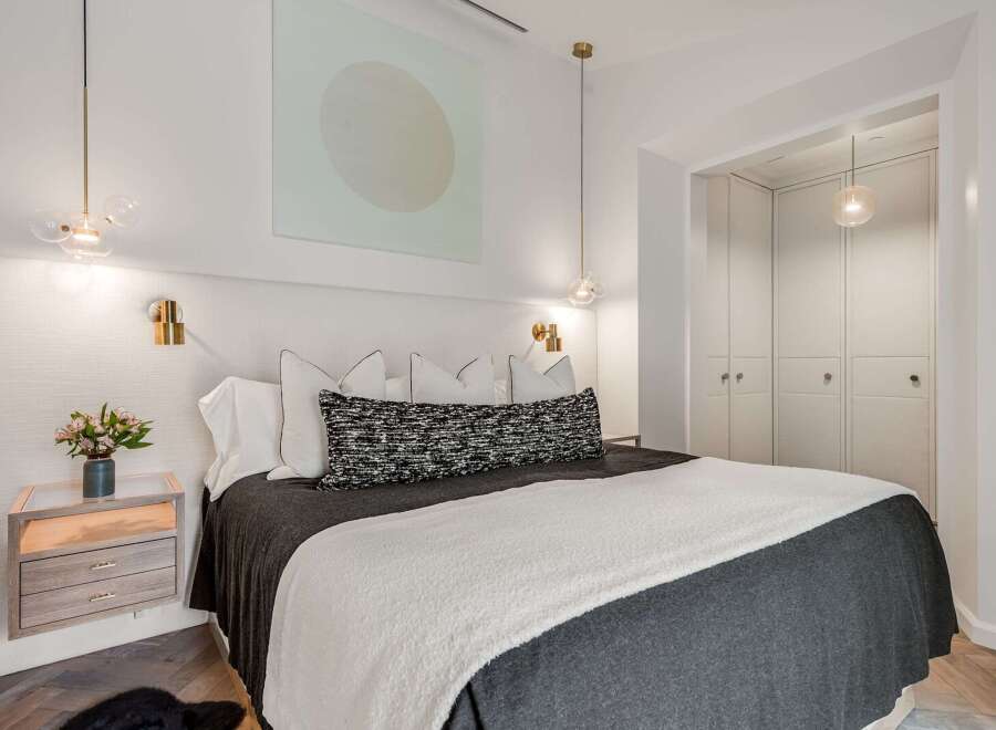 Experience modern luxury in this beautifully appointed bedroom, featuring a plush king-sized bed adorned with elegant linens and decorative pillows.
