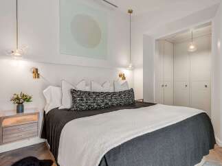 Experience modern luxury in this beautifully appointed bedroom, featuring a plush king-sized bed adorned with elegant linens and decorative pillows.