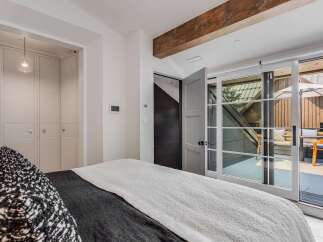 Experience modern luxury in this stunning bedroom featuring a plush bed with a textured throw and a striking black and white accent pillow.
