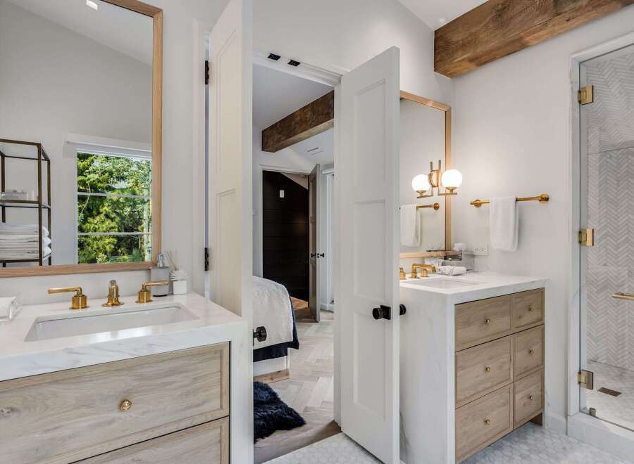Experience modern luxury in this stunning bathroom featuring a dual-sink vanity with marble countertops and warm wood cabinetry.