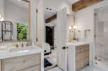 Experience modern luxury in this stunning bathroom featuring a dual-sink vanity with marble countertops and warm wood cabinetry.