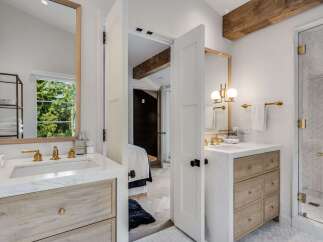 Experience modern luxury in this stunning bathroom featuring a dual-sink vanity with marble countertops and warm wood cabinetry.